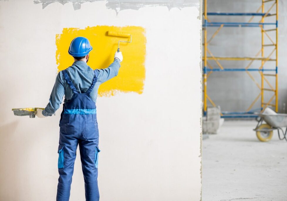 painting wall with yellow paint at the construction site indoors